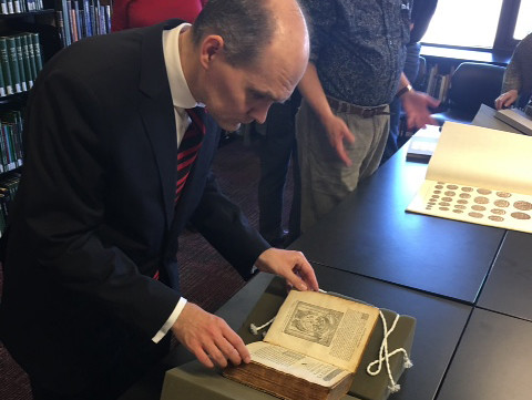 Dr. Woytek examining a 1567 edition of works by Guillaume Du Choul